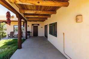 A covered outdoor area with a concrete floor, wooden beams, a door, and a window.