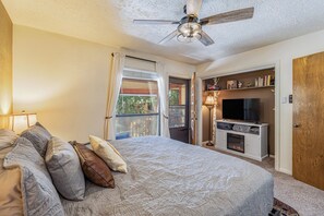 Ein Schlafzimmer mit einem Bett, einem Deckenventilator, einem Fernseher und einem Kamin.