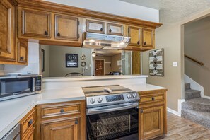 A kitchen with wooden cabinets, a microwave, a stove, and an oven. - Tenderfoot Retreat - Creekside, Near Ski & Town (Red River)