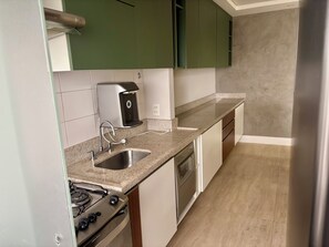 A kitchen with a gas stove, a built-in dishwasher, a coffee maker, and a sink. - 36th floor, Panoramic View - Itaim - 2 suites, 2 parking spaces (São Paulo)