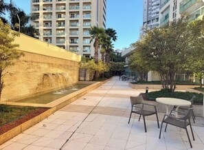 Un patio con fuente de agua, mobiliario exterior y edificios circundantes.