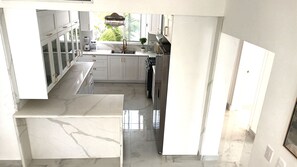 Eine moderne Küche mit weißen Schränken, einem Edelstahlkühlschrank und einer Marmorarbeitsplatte.