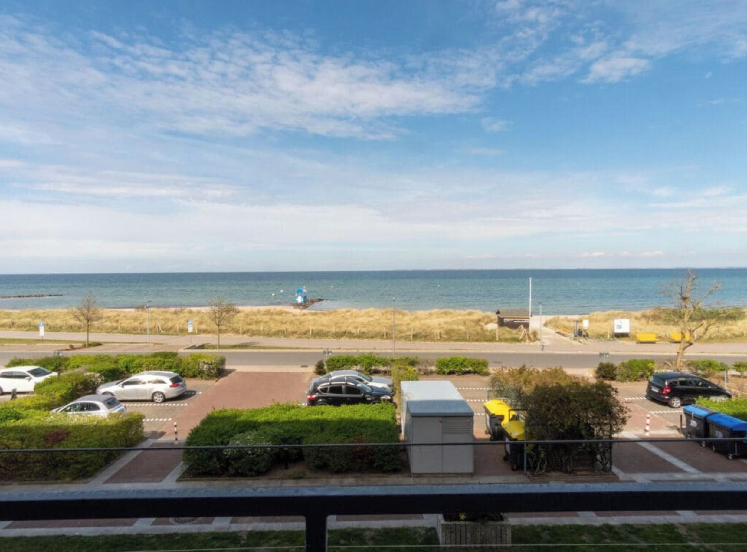 Une vue sur la côte, avec un espace de stationnement, une plage et un ciel dégagé.