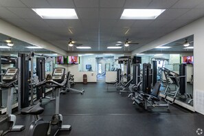 A gym with various exercise machines, mirrors, and a television screen. - Landing | Beautiful 1BD, Gym, Clubhouse (Murfreesboro)