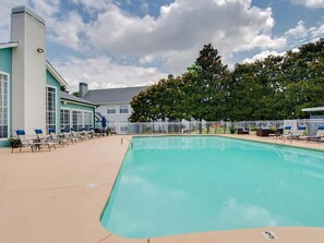 A swimming pool with lounge chairs and a building with large windows. - Landing | Beautiful 1BD, Gym, Clubhouse (Murfreesboro)