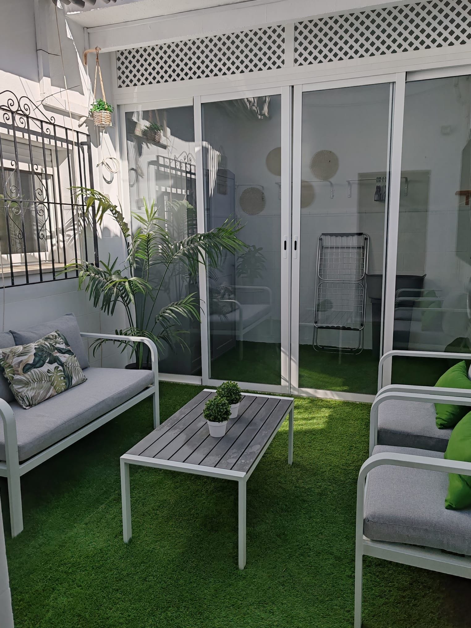 A patio with a white sofa, a small table, and potted plants.