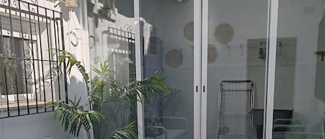 A patio with a white sofa, a small table, and potted plants.