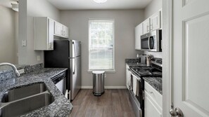 A compact kitchen with a stainless steel refrigerator, microwave, stove, and sink. - Landing | Beautiful 1BD, Clubhouse, Gym (Murfreesboro)