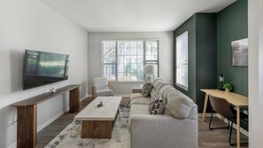 A modern living room with a flat-screen TV, a sofa set, a coffee table, and a desk with a chair. - Landing | Beautiful 1BD, Clubhouse, Gym (Murfreesboro)