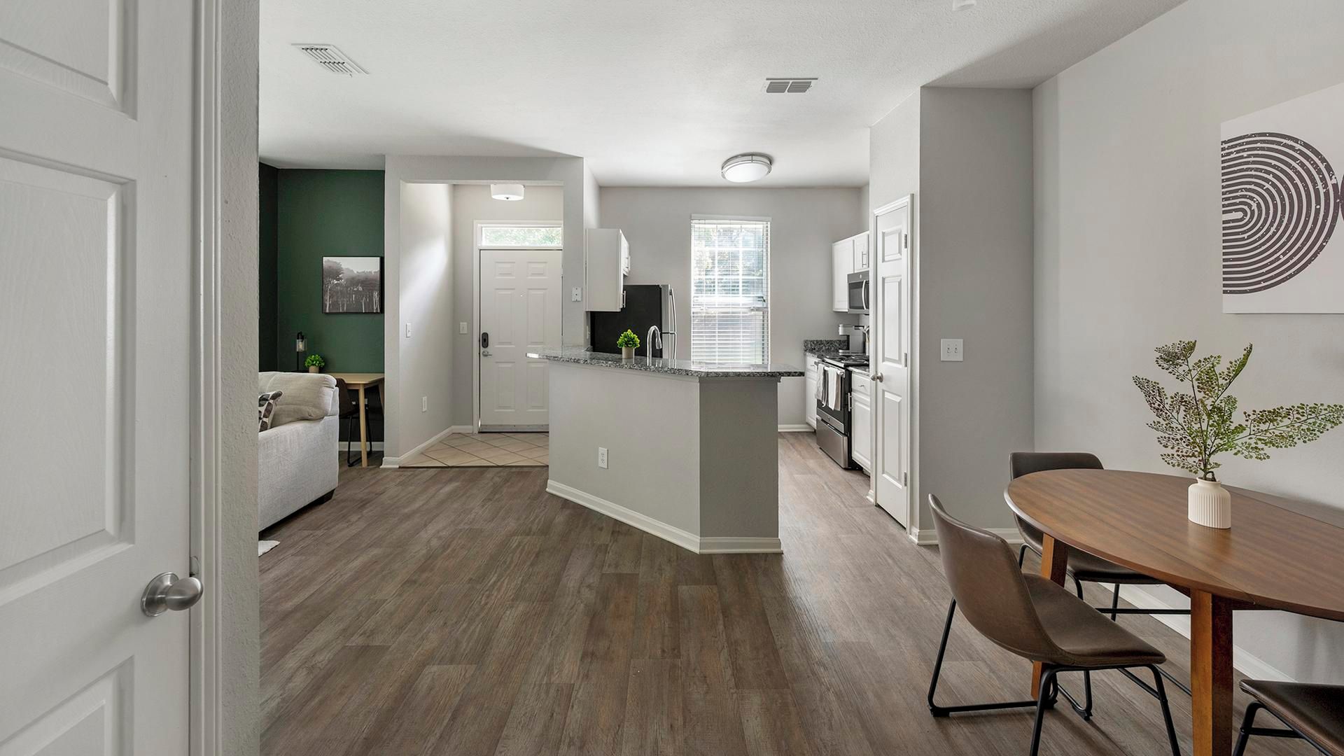 Una cocina moderna con una isla central, un comedor con mesa de madera y una sala de estar con sofá.