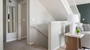 Ein modernes Interieur mit Treppe, Spiegel, Lampe und Sofa.