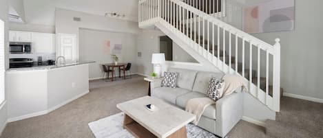 Un espacio habitable moderno con una escalera, una cocina y un comedor.