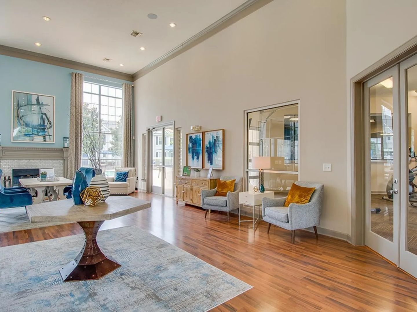 A spacious living room with hardwood flooring, a central coffee table, and seating arrangements including a sofa and armchairs.