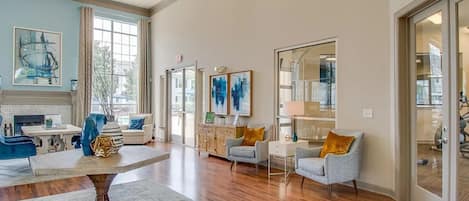 A spacious living room with hardwood flooring, a central coffee table, and seating arrangements including a sofa and armchairs.