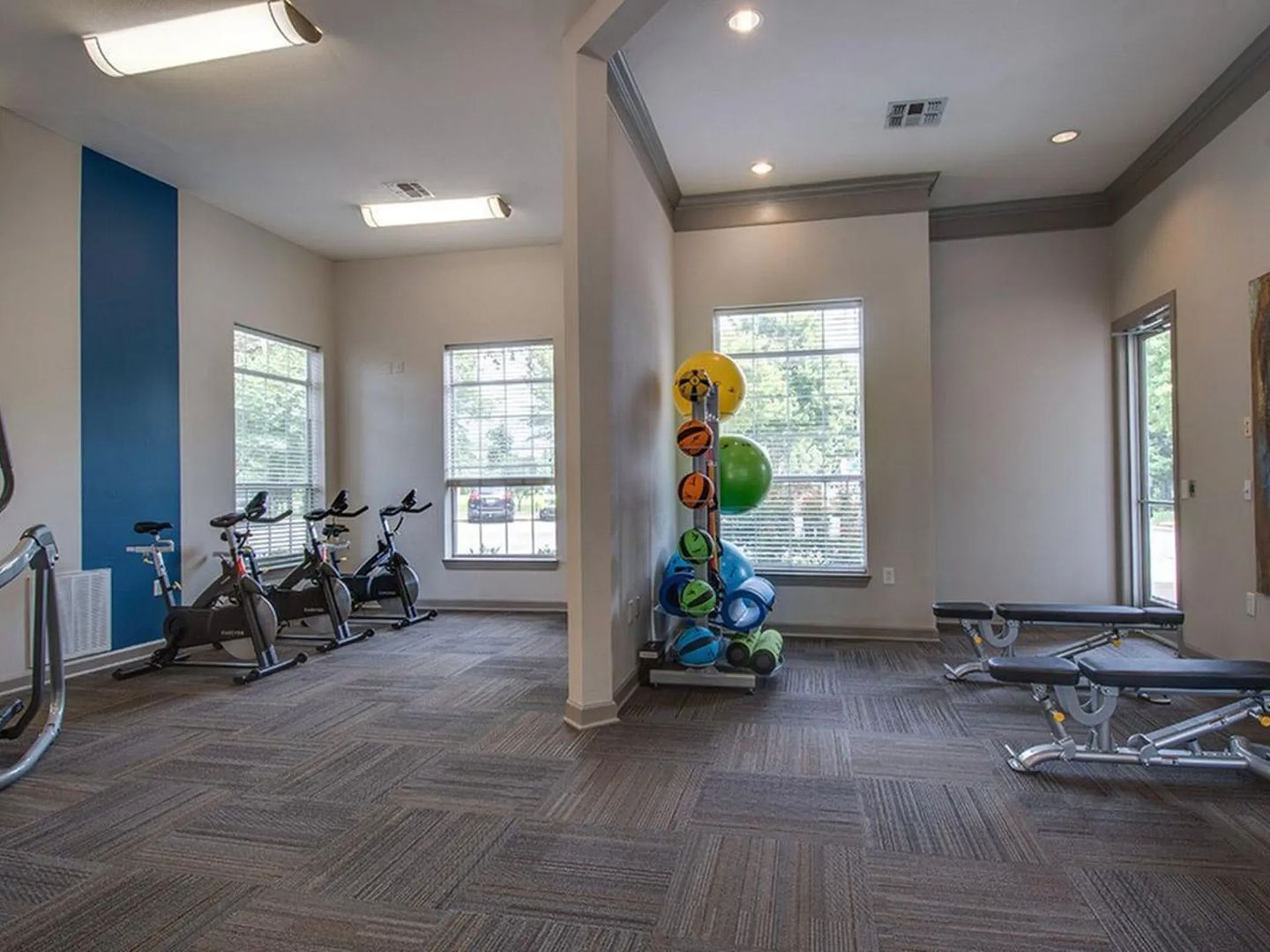 A gym with stationary bikes, exercise balls, and benches.