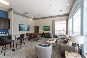 A modern living room with a dining area, a TV, and a large window with blinds. - Landing | Stylish 1BD, Gym, Clubhouse (Murfreesboro)