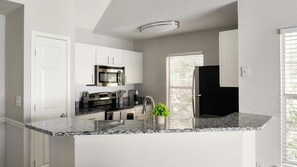 A modern kitchen with white cabinetry, a stainless steel oven, and a granite countertop. - Landing | Stunning 2BD, Clubhouse, Gym (Murfreesboro)