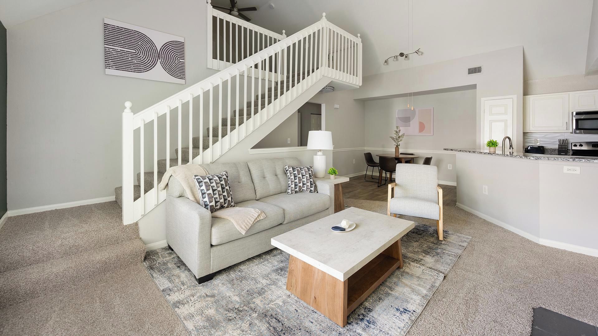 Una sala moderna con una escalera, un comedor y una cocina.
