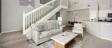 Una sala moderna con una escalera, un comedor y una cocina.