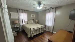 Ein Schlafzimmer mit einem Himmelbett, einem Deckenventilator und einem Fernseher auf einem Holzboden.