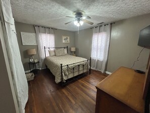 A bedroom with a four-poster bed, a ceiling fan, and a television on a wooden stand. - Lovely 2-bedroom house with AC in cool Russell (Russell)