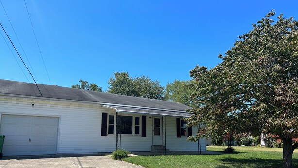 Ein eingeschossiges Haus mit Garage, überdachter Veranda und Rasen.