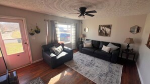 Ein Wohnzimmer mit einer Couch, einem Sessel und einem Deckenventilator.