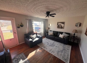 A living room with a sofa, armchair, and a ceiling fan. - Lovely 2-bedroom house with AC in cool Russell (Russell)