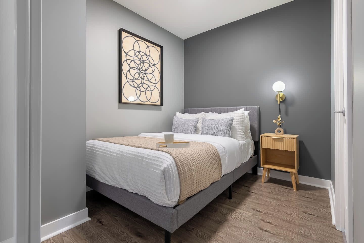 A bedroom with a bed, bedside table, and a wall-mounted light fixture.