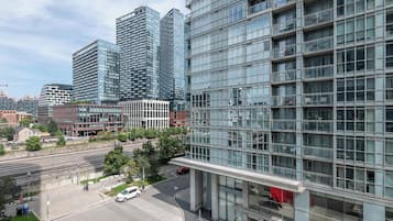 A modern building with a glass facade, a parking area, and a train track in the foreground.
