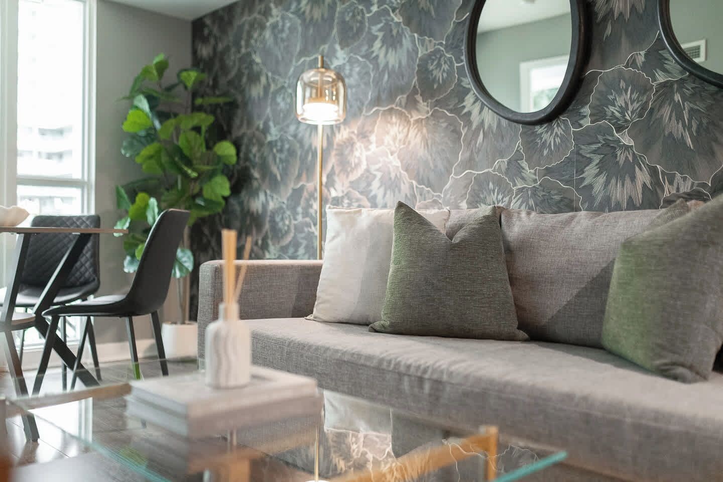 Uma sala de estar moderna com um sofá, uma mesa de centro de vidro e um abajur.