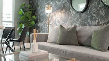 Uma sala de estar moderna com um sofá, uma mesa de centro de vidro e um abajur.