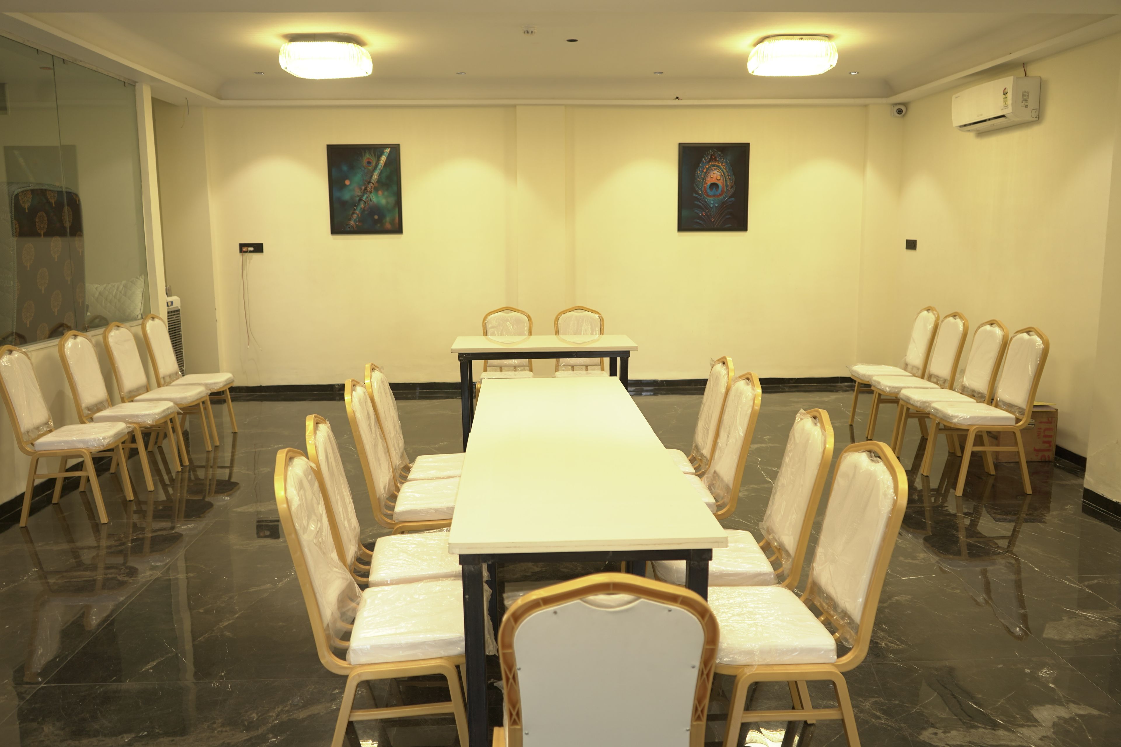 A conference room with a long table and chairs, two paintings on the walls, and an air conditioning unit.