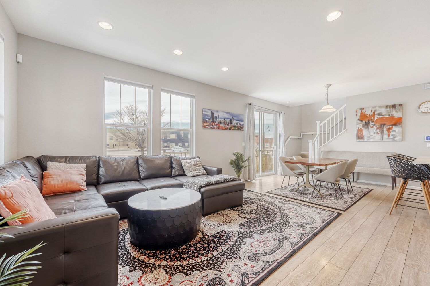 A modern living room with a leather sofa, a round coffee table, and a dining area with a table and chairs.