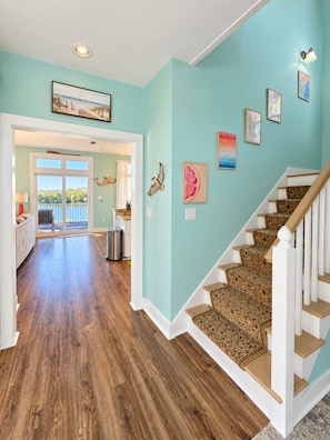 A spacious hallway with wooden flooring leading to a staircase with patterned carpet.