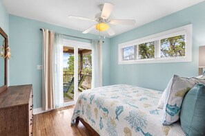 A bedroom with a bed, a ceiling fan, a window, and a view of the outdoors. - Crosswinds Cottage - Private Waterfront Escape Off The Runway + Golf Cart (Cedar Key)