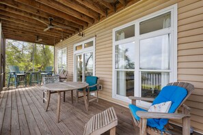 A covered outdoor area with wooden flooring, a round table, and several chairs. - Crosswinds Cottage - Private Waterfront Escape Off The Runway + Golf Cart (Cedar Key)