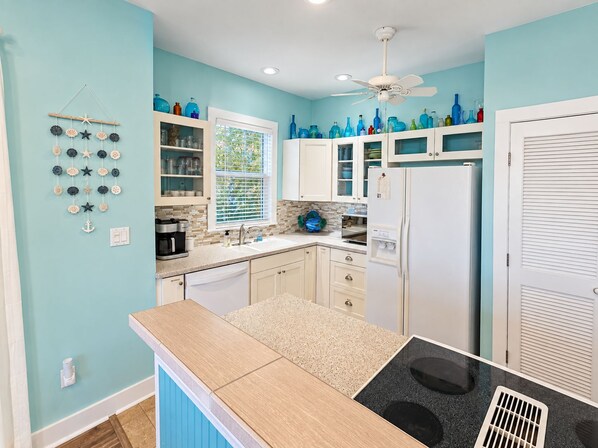 A kitchen with white cabinets, a central island, and a ceiling fan.