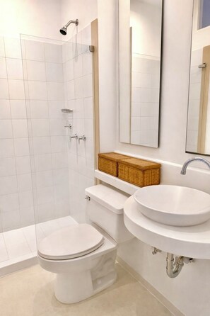 Un baño moderno con inodoro blanco, ducha y lavamanos.