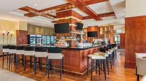 A bar area with a wooden bar counter, multiple stools, and a television screen. - 2-bedroom hotel suites in peaceful Orlando walking distance to Universal (Orlando)