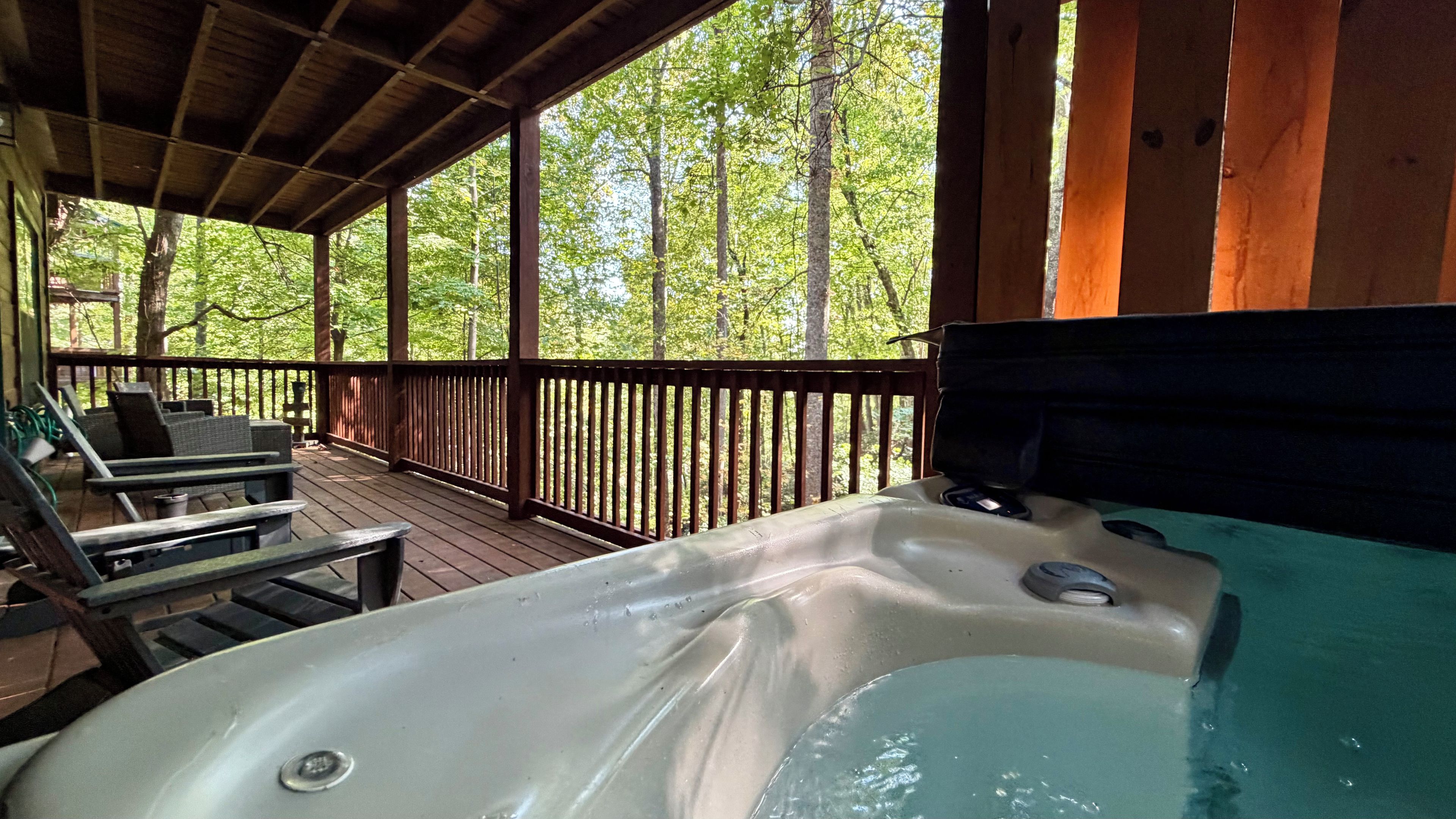 Un bain à remous sur une terrasse en bois, avec vue sur les arbres.