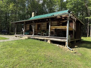 A rustic cabin with a porch, outdoor seating, and a covered area. - Rustic Charm meets Woodland Peace • Where every sunrise is a blessing (Pleasantville)