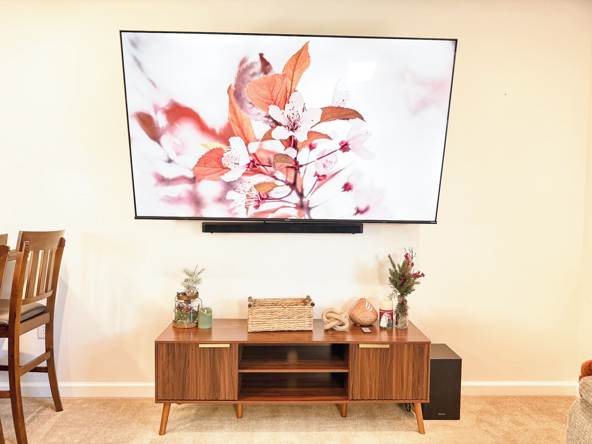 A flat-screen TV mounted on a wall above a wooden console table with decorative items.