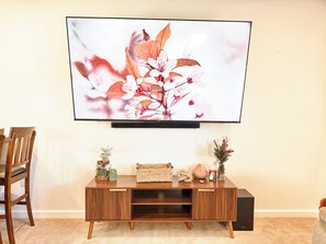 Et fladskærms-tv ophængt på væggen over et træbord med dekorative genstande.