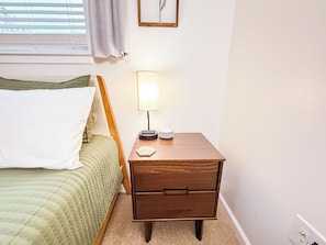 A bedroom with a bed, a bedside table with a lamp, and a wall clock.