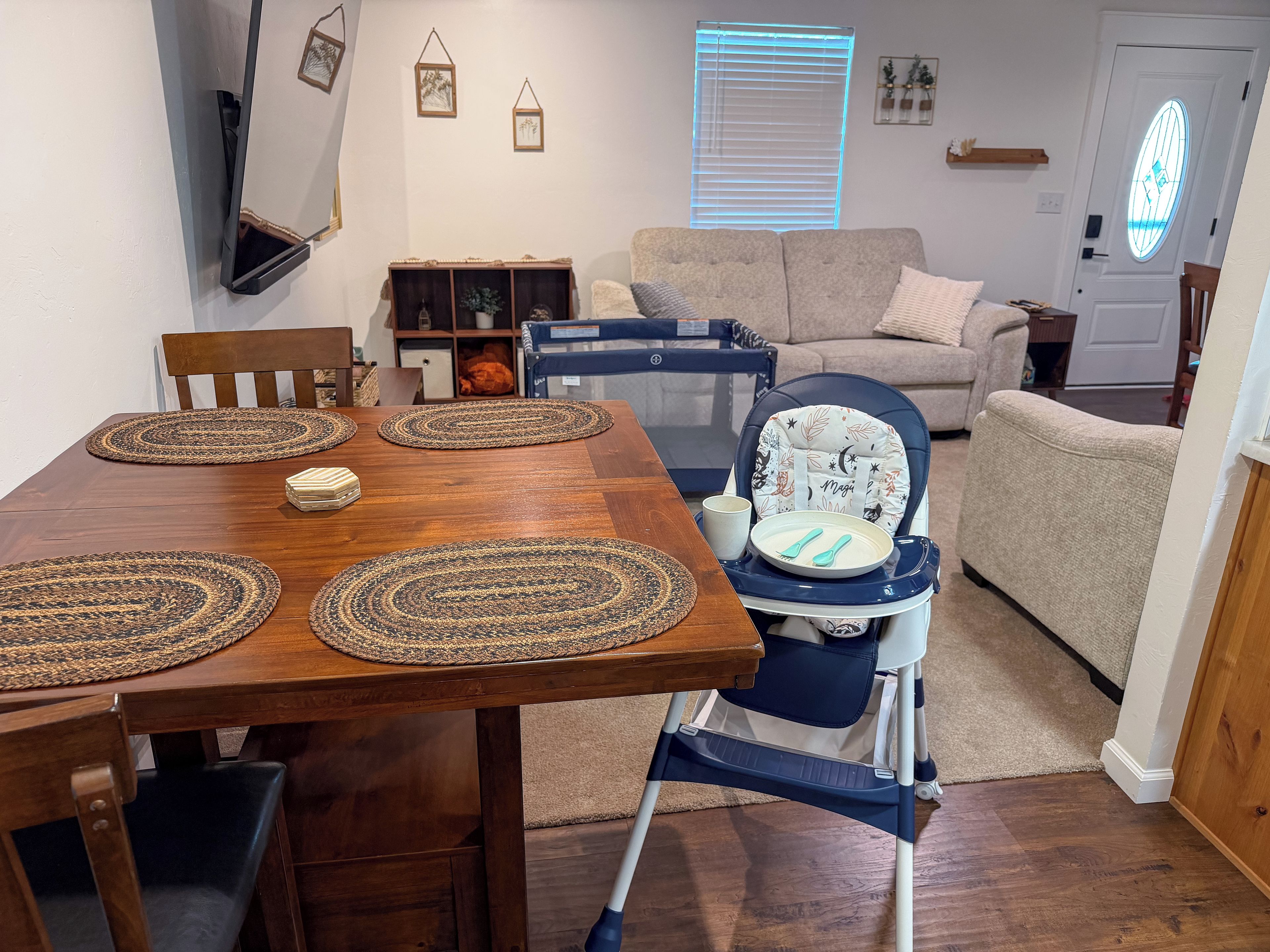 Un coin repas avec une table en bois, des sets de table et une chaise haute avec un plateau.