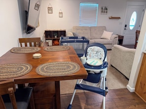 A dining area with a wooden table, placemats, and a high chair with a tray.