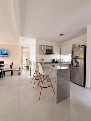 A modern kitchen with a central island, stainless steel appliances, and a dining area with a TV. - Welcome to MA Cartagena • Playa • Piscina (Bolívar)