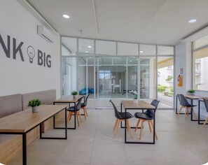 A modern office space with glass partitions, wooden tables, and black chairs. - Welcome to MA Cartagena • Playa • Piscina (Bolívar)
