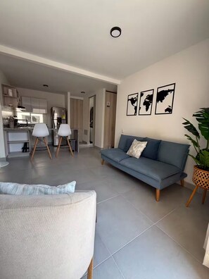 A modern living room with a sofa, a dining area, and a kitchen in the background. - Welcome to MA Cartagena • Playa • Piscina (Bolívar)